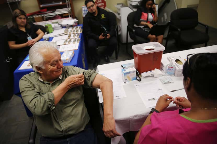 Gavino Saldivar, of DeSoto, Texas, lifts his sleeve up before receiving an influenza vaccine...