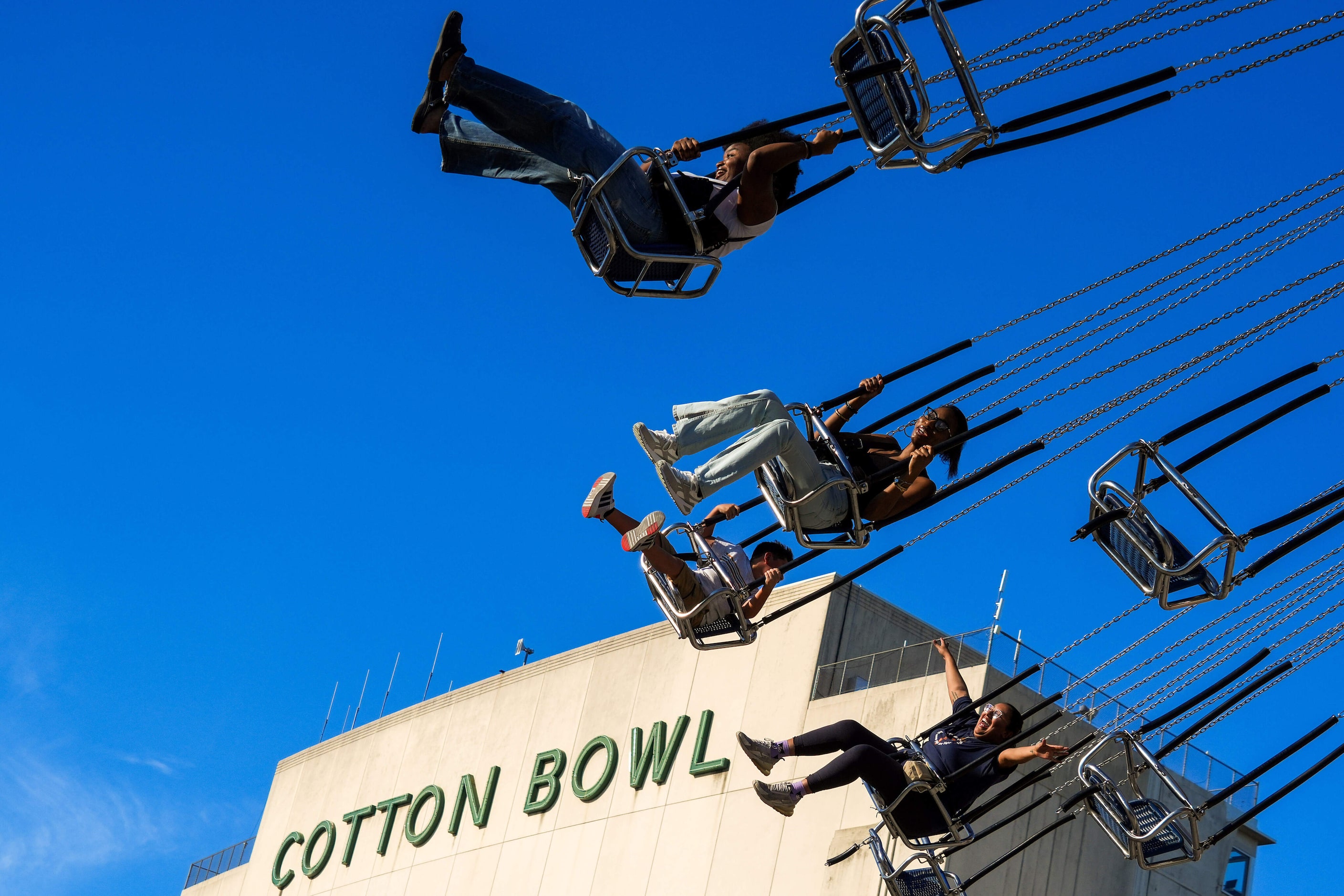 Fairgoers ride the Wave Swinger ride on the midway at the State Fair of Texas on Sunday,...