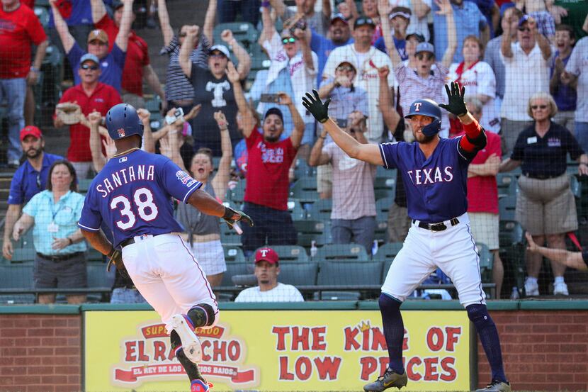 Texas Rangers Danny Santana (38) is greeted by teammate Hunter Pence, right, after scoring...
