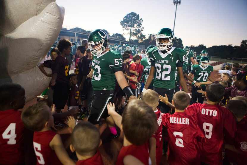 Arlington is greeted by kids before entering the tunnel during a high school football...