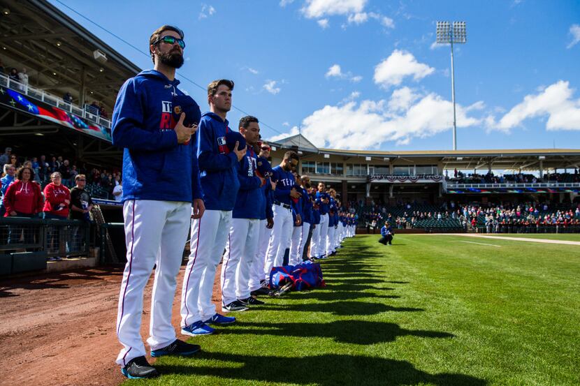 The Texas Rangers, lead by starting pitcher Cole Hamels (35, left) line up as the national...
