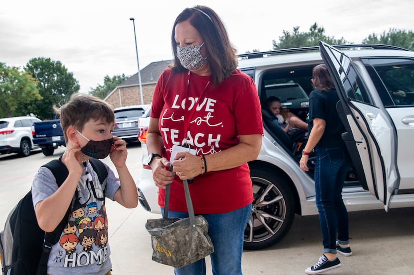 Inclusion aide Renee Grebe (center) holds the lunchbox of second grade student Ethan Sparks...