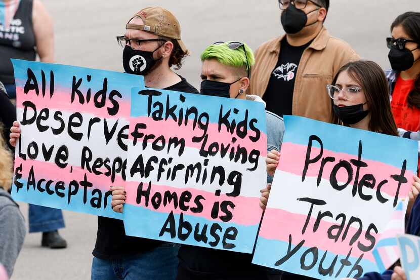Protesters carry signs during the "Trans Kids Cry For Help" rally outside Texas Governor...
