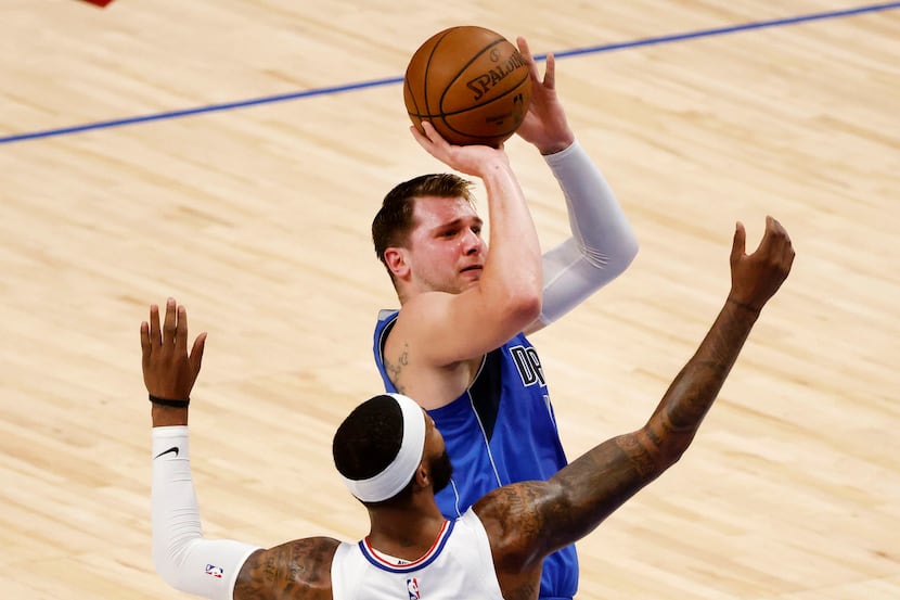 Dallas Mavericks guard Luka Doncic, top, shoots a three-point basket in front of Los Angeles...