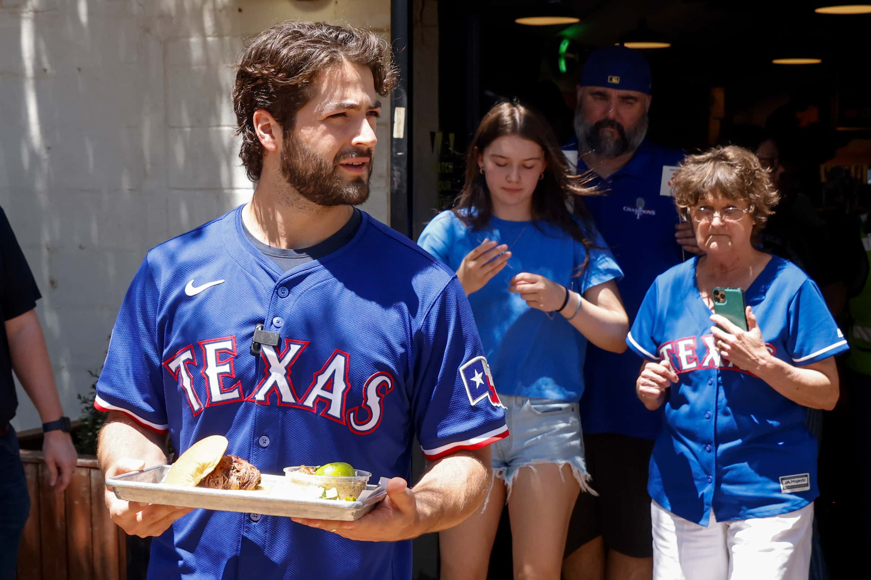 Texas Rangers third baseman Josh Smith carries a tray of barbecue to customers at Hurtado...