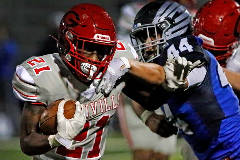 Greenville High School running back Ottugas Johnson (21) is slowed down by North Forney High...