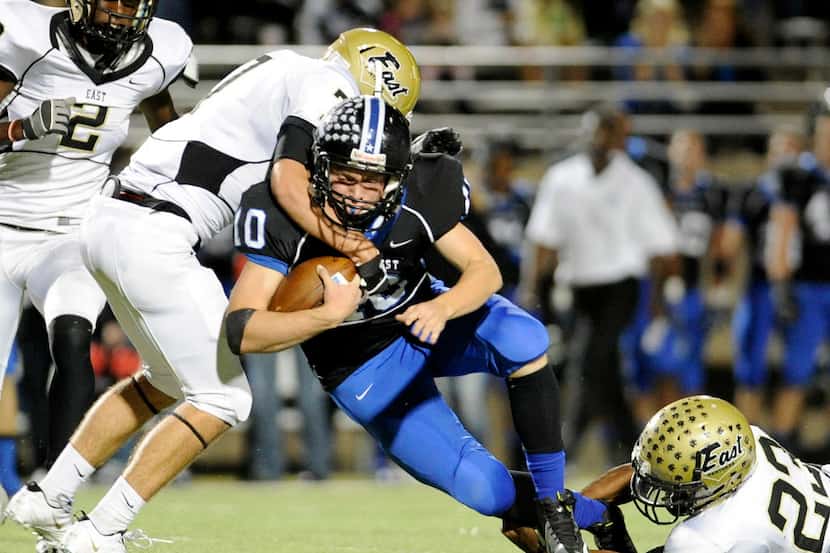 Plano East's Zack Mueller and Michael Miller (23) tackle Plano West's Travis Korry during a...