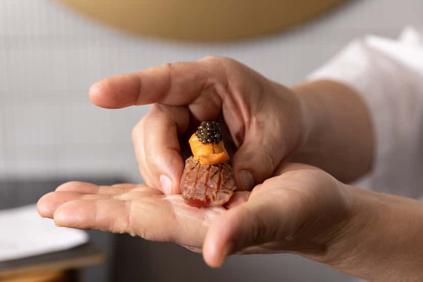 Executive chef Shinichiro Kondo holds sushi topped with seared fatty tuna, sea urchin and...