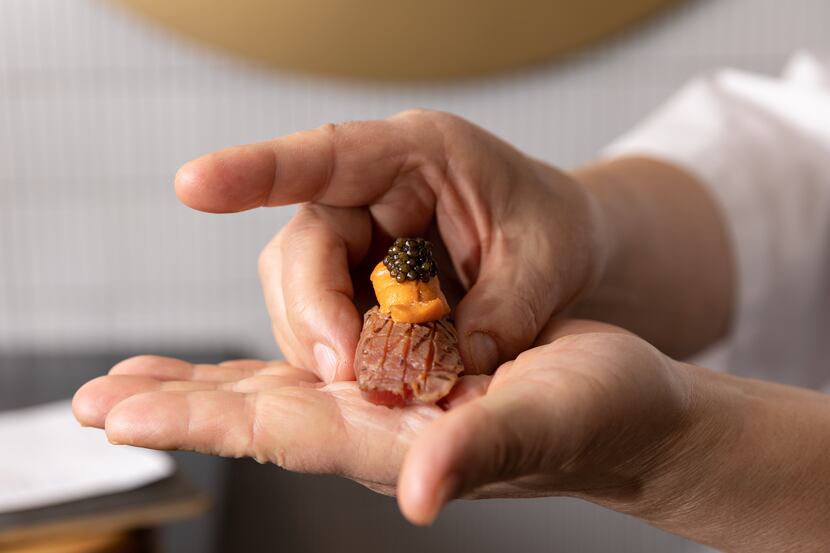 Executive chef Shinichiro Kondo holds sushi topped with seared fatty tuna, sea urchin and...