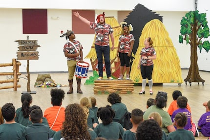 Performers act our a scene on front of seated schoolchildren.