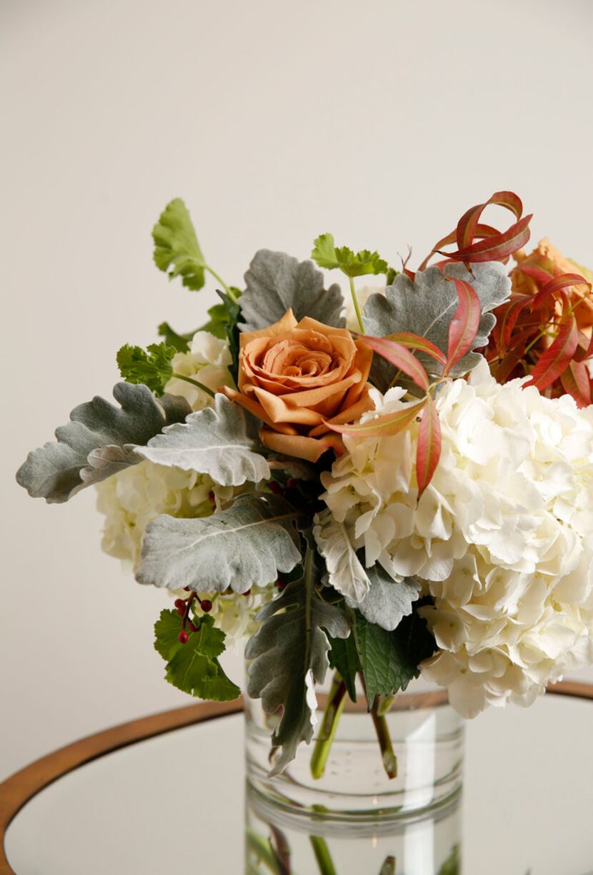 Floral arrangement including hydrangeas, Combo rose, geranium leaves, dusty miller and...