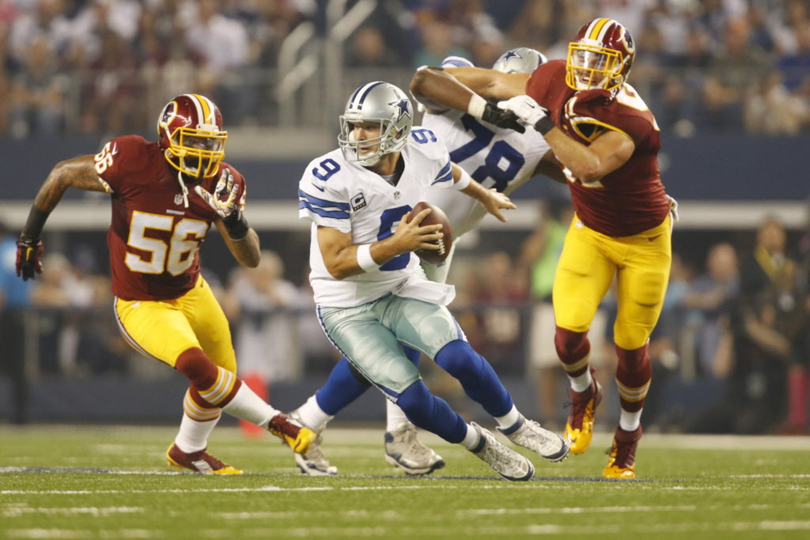 Dallas Cowboys quarterback Tony Romo (9) scrambles away from the defensive pressure in the...