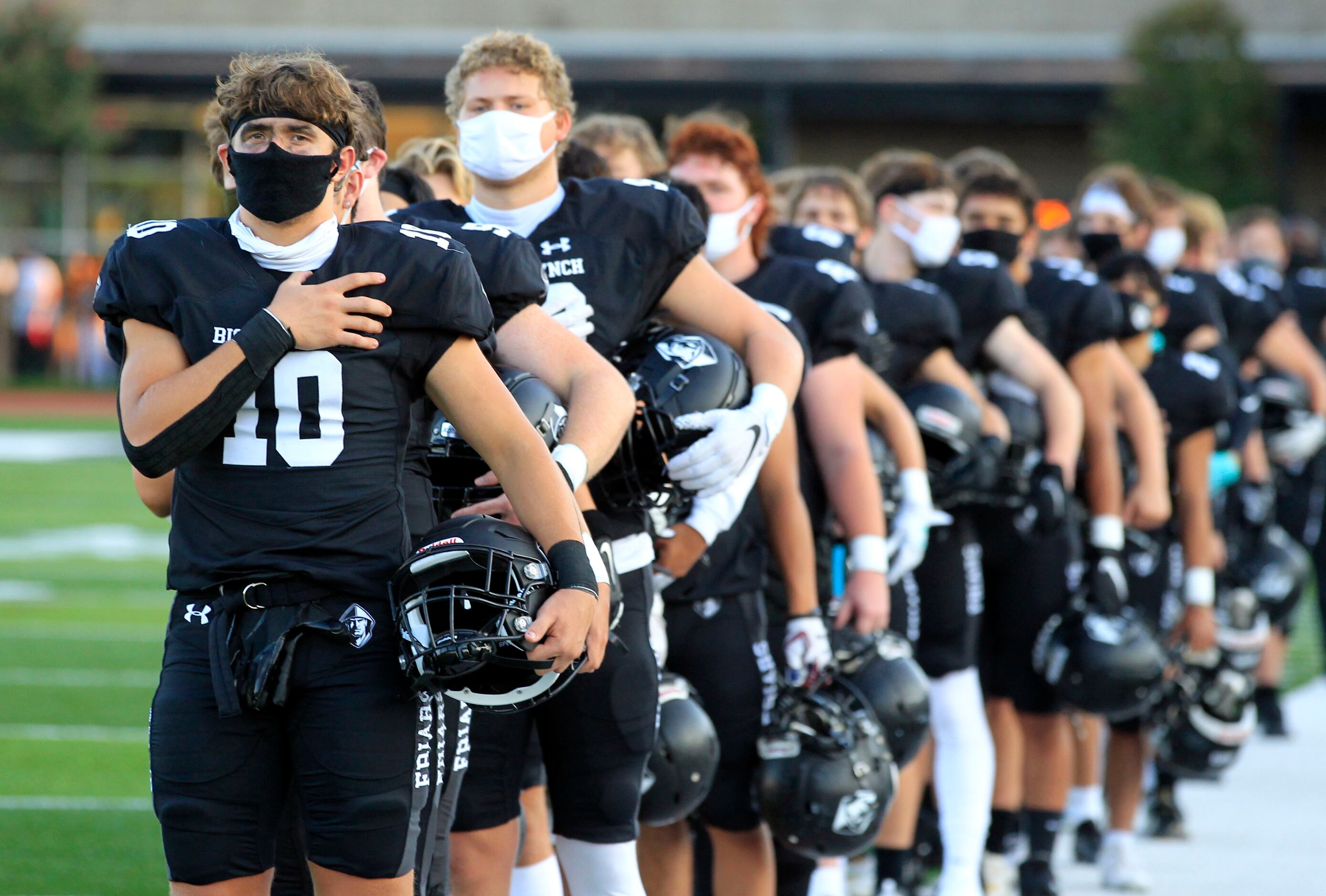 Bishop Lynch’s LB Logan Monroe (10) stand for the national anthem before the first half of...
