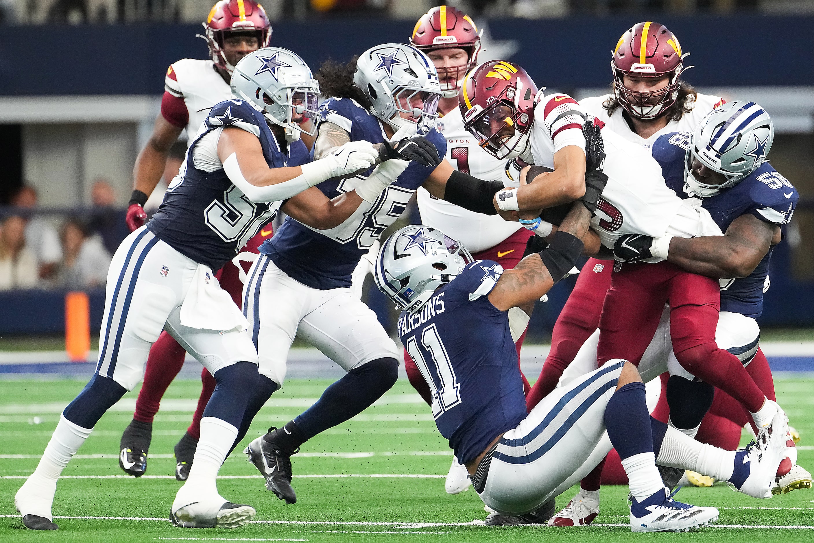 Washington Commanders quarterback Jayden Daniels (5) is brought down by Dallas Cowboys...