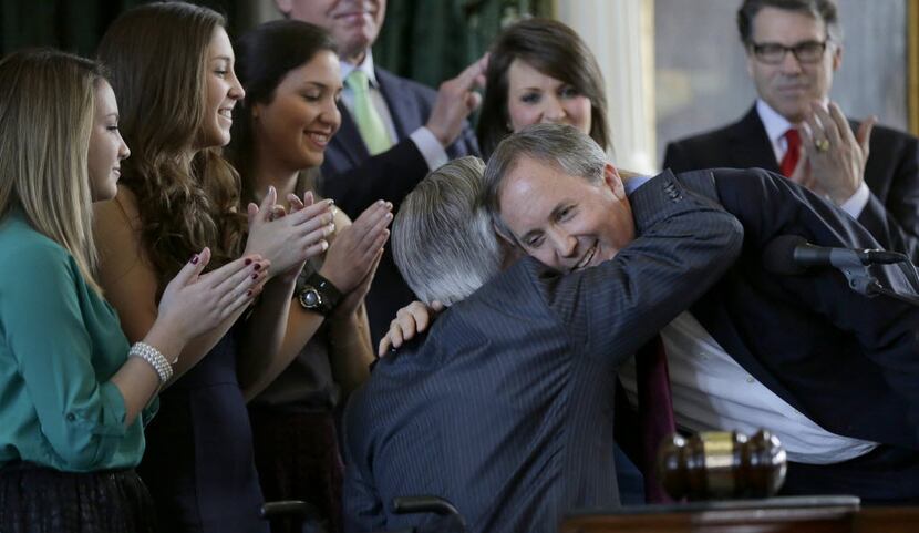 Ken Paxton (right) embraces Gov.-elect Greg Abbott after Paxton was sworn in as the Texas...