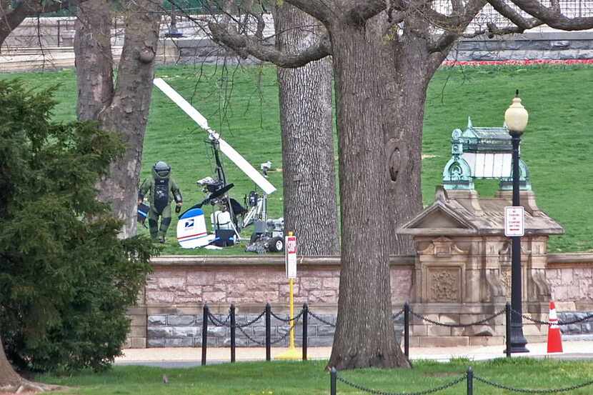 
A bomb squad technician walks past the gyrocopter that Doug Hughes landed on the grass in...