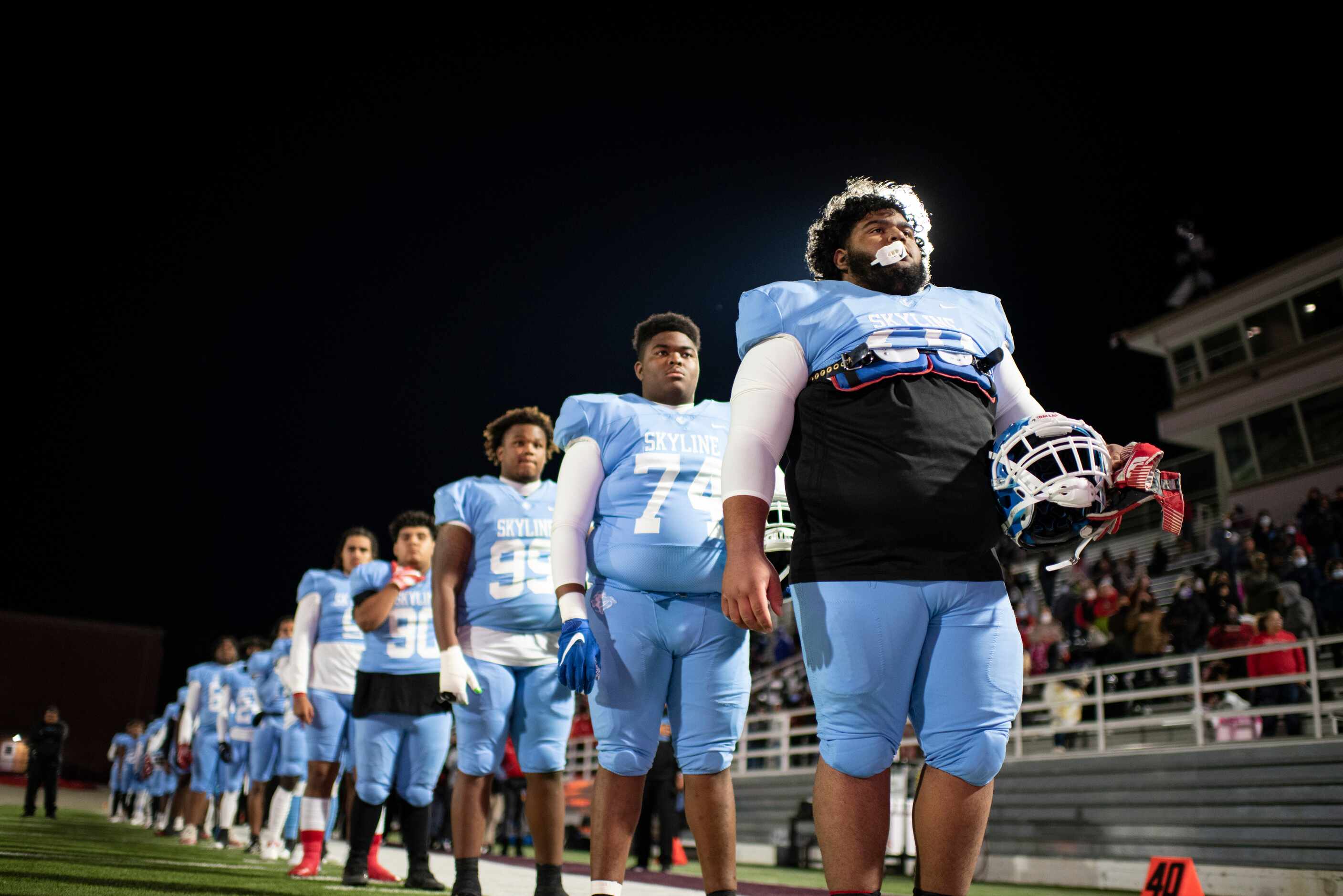 Skyline junior Chris Vestal (78) stands in front of his teammates during the national anthem...