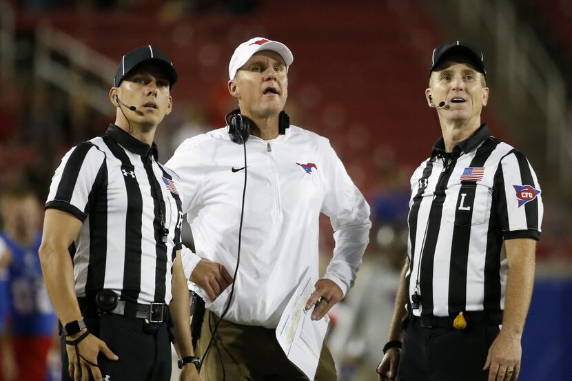 Southern Methodist Mustangs head coach Chad Morris (center) watches an instant replay on the...