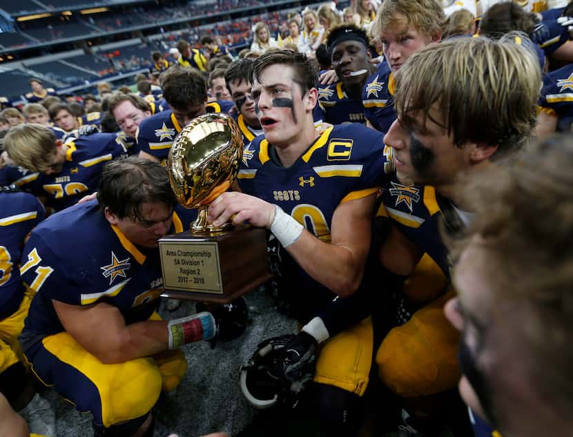 Highland Park's James Herring (30) holds the trophy as players gather for a group photo...