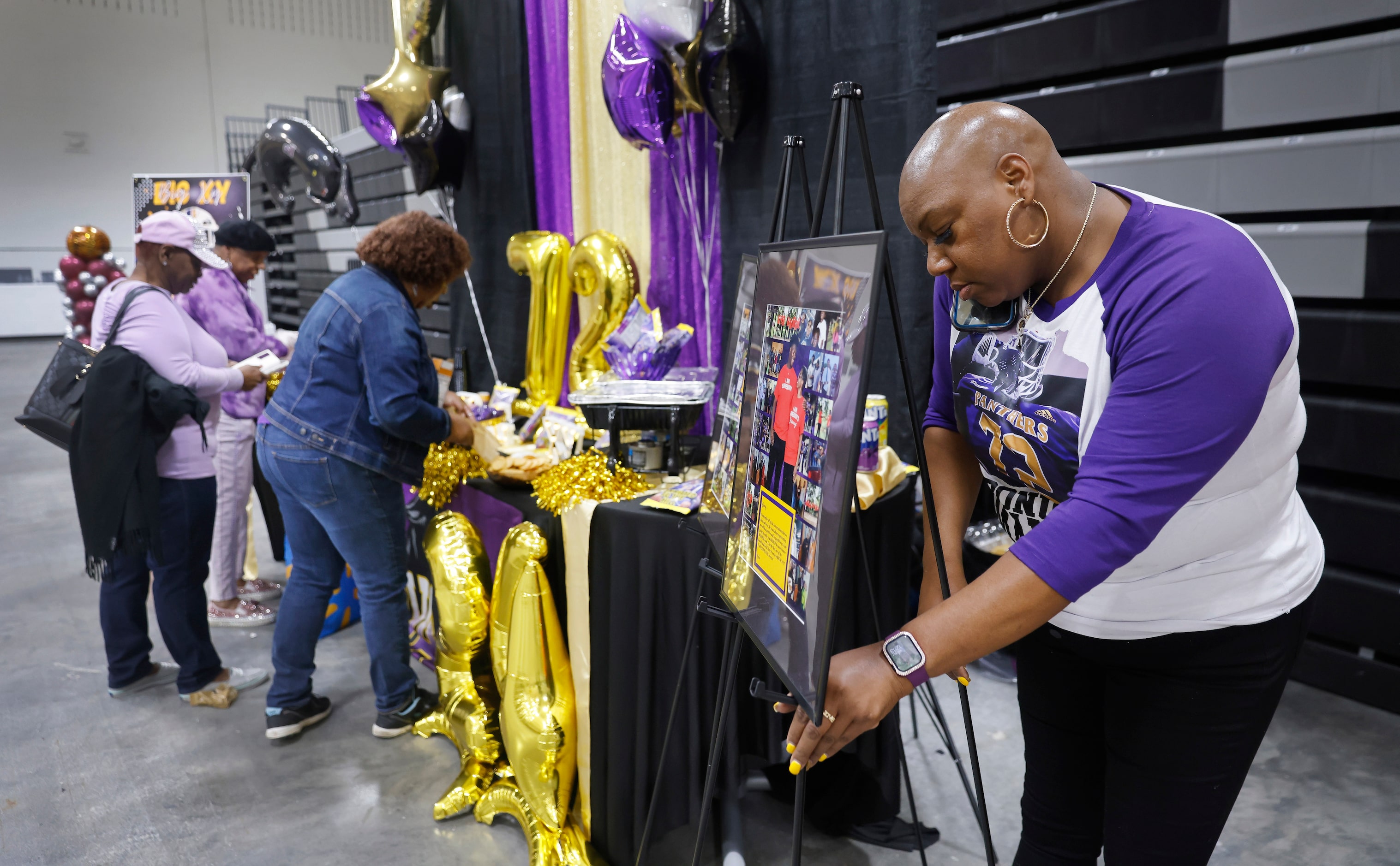 Jacquesha Hunt (right) helps set up a display honoring South Oak Cliff football player Xyler...