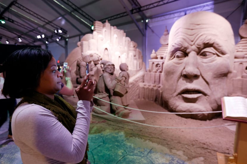Kendra McGowan takes a photo of sand sculptures depicting Dorothy, Toto, Cowardly Lion, Tin...
