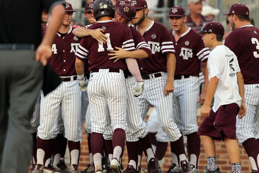 Texas A&M's J.B. Moss (11) is swarmed by teammates after hitting a home run against TCU...