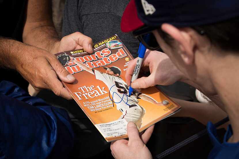 Texas Rangers pitcher Tim Lincecum signs autographs for fans after a spring training workout...