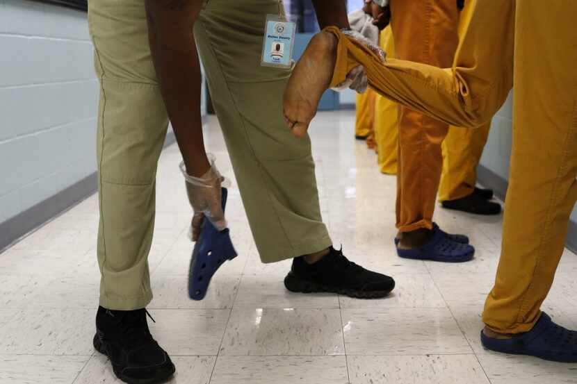 Frederick Faulk, juvenile supervision officer, takes off the shoe of an inmate during a...