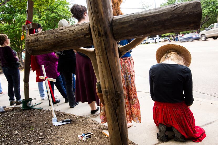 Abortion opponents kneel in prayer as they line Greenville Avenue during the Good Friday...