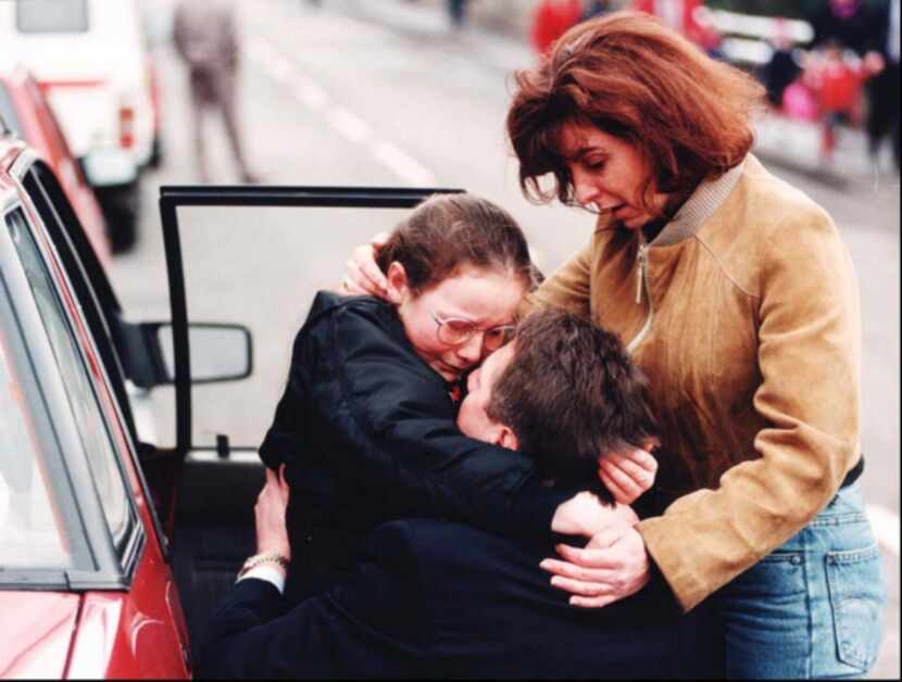 An unidentified mother and father embrace their uninjured daughter outside the elementary...