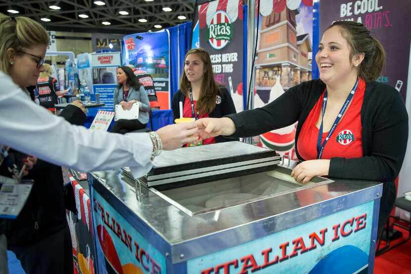 Emily Lewis hands a sample of mango ice to a visitor to the Rita's Italian Ice booth at...