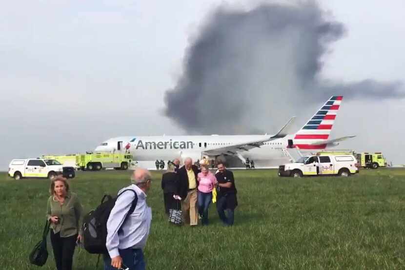 Passengers walk away from a burning American Airlines jet that aborted takeoff and caught...