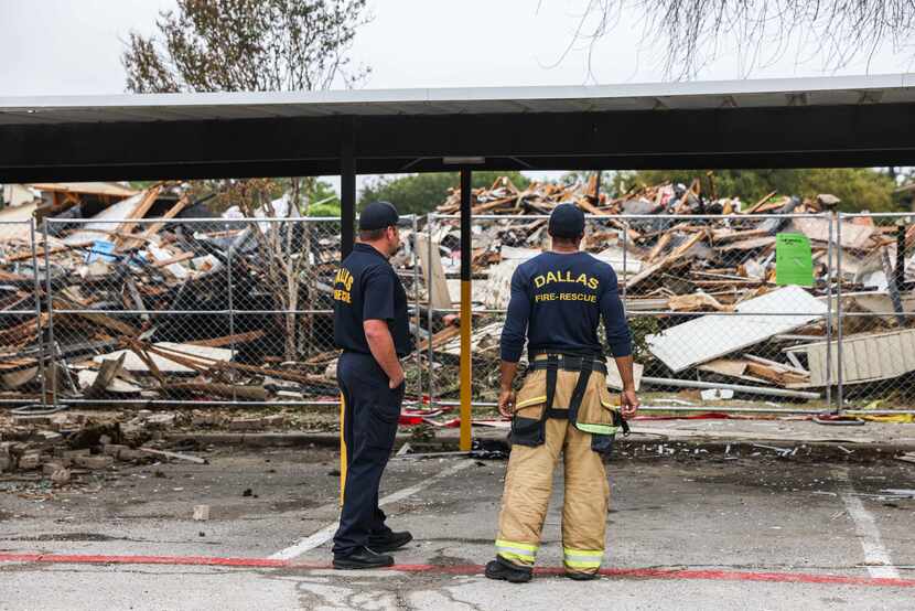 Officers fro Dallas Fire-Rescue stands in front of debris from an exploded apartment...
