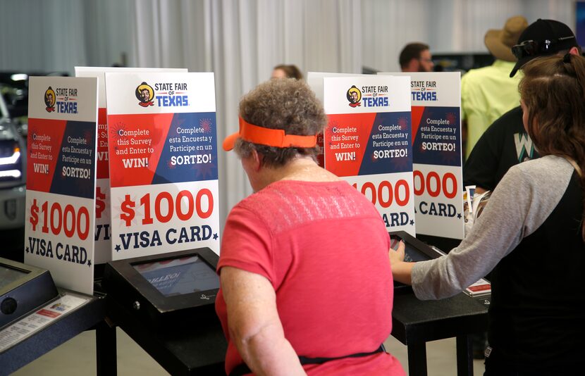 Fairgoers fill out a survey with the chance to win a prize in one of the automobile...