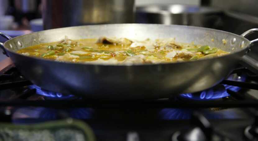 Tina Danze moves the paella  pan to two burners. 