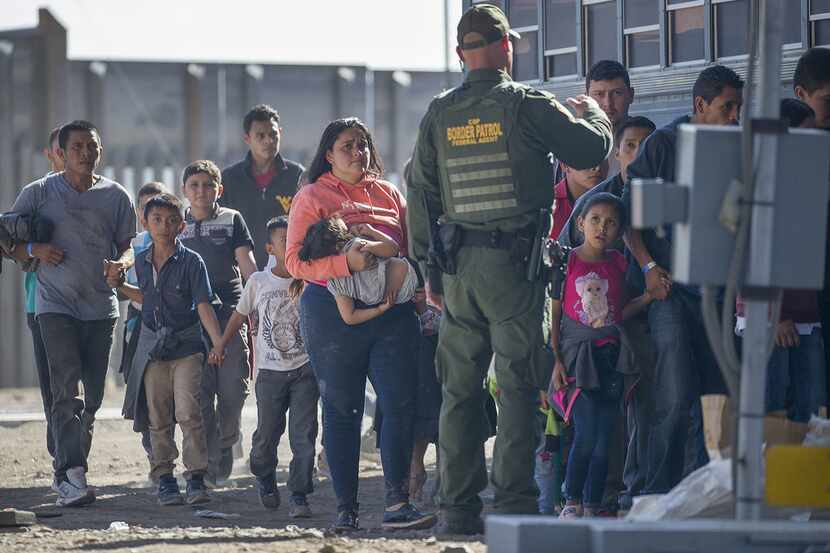 Migrants are loaded onto a bus by U.S. Border Patrol agents after being detained when they...