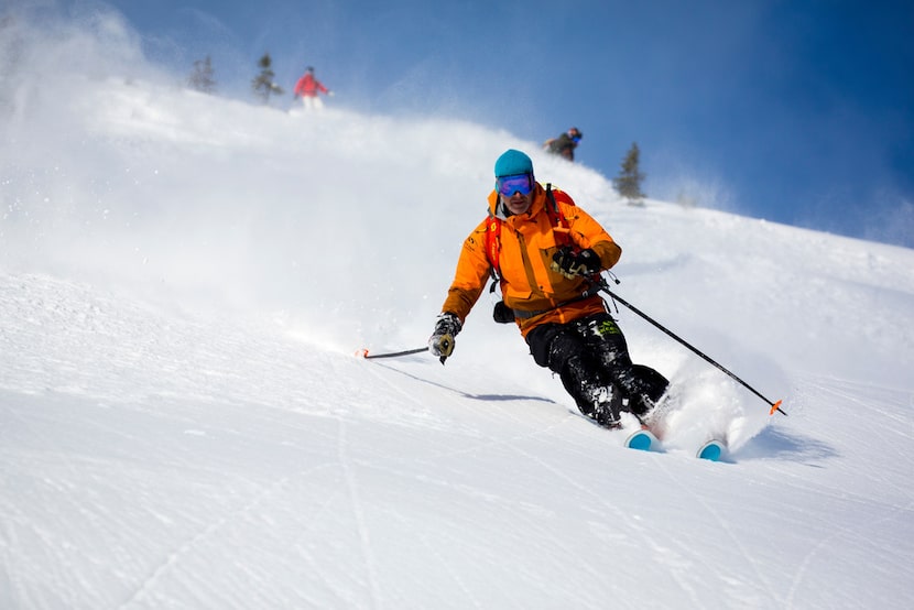 Happy heli-skiers enjoy a bluebird day of wilderness downhill adventure with Skeena...