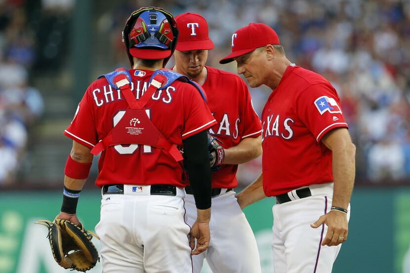Texas Rangers manager Jeff Banister, right, talks with Robinson Chirinos, left, and starting...