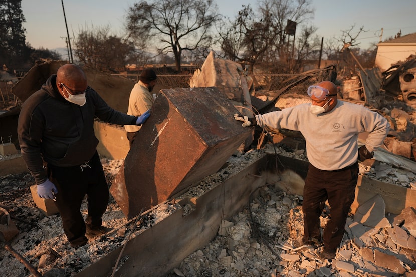 FILE - Kenneth Snowden, left, surveys the damage to his fire-ravaged property with his...