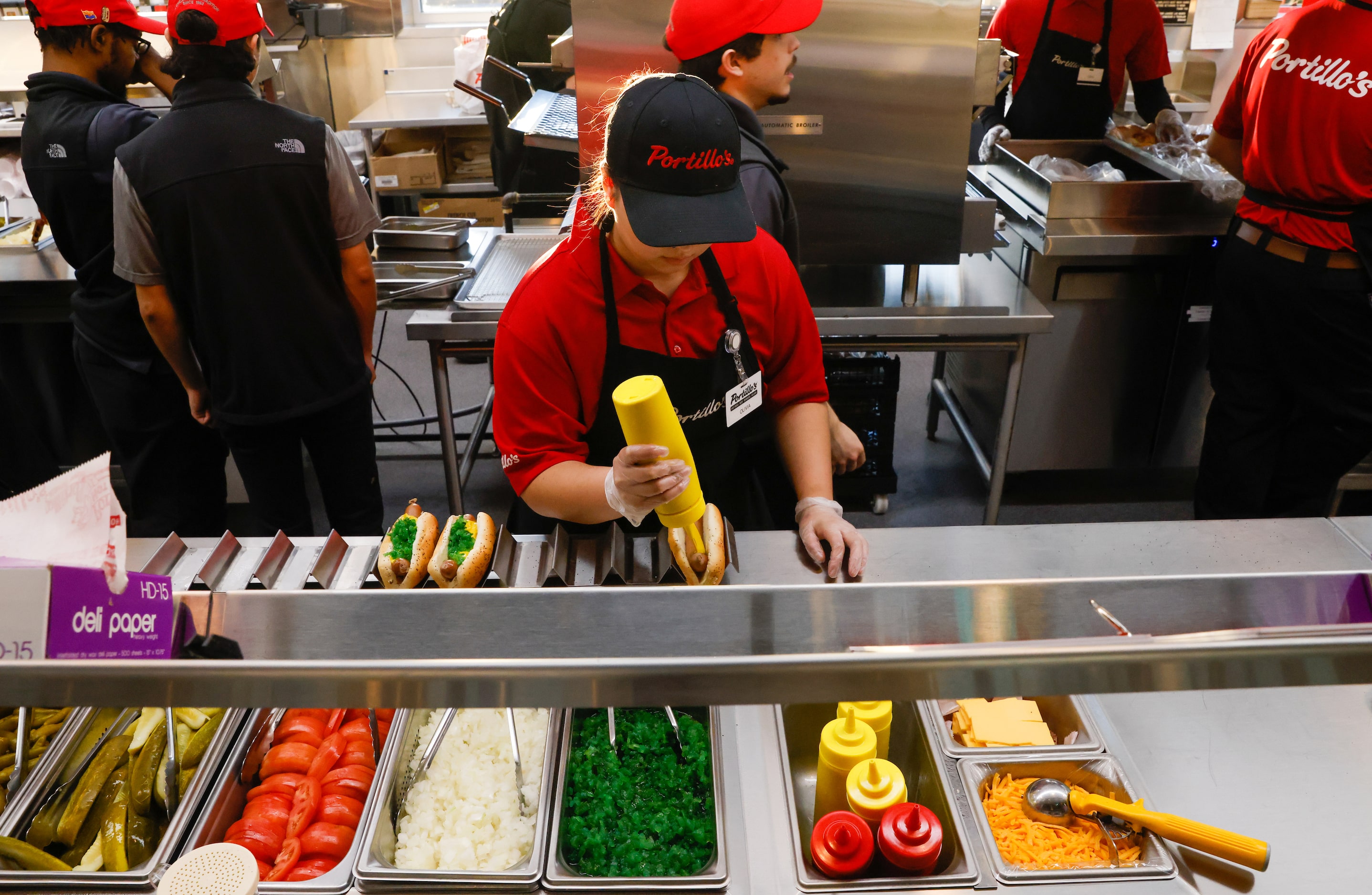 Portillo’s team member Olivia Arista (center) prepares some of Portillo’s first orders at...