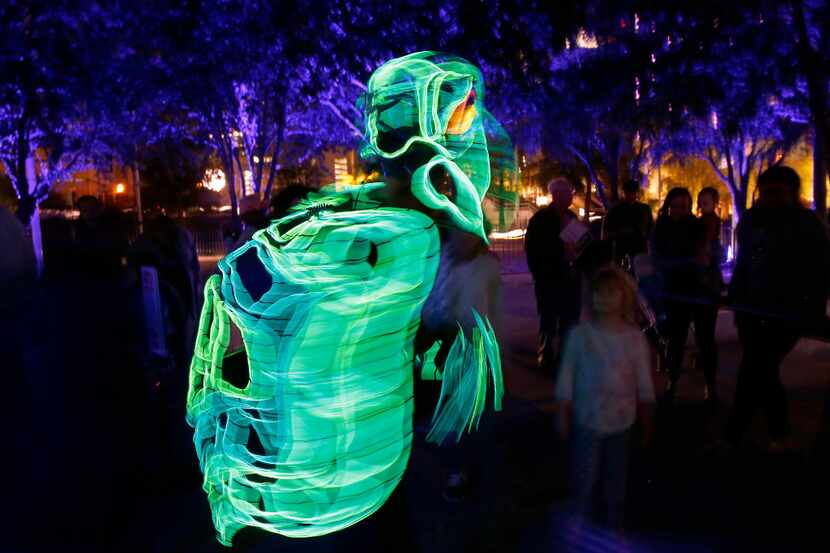 People watch dancer Kevin Lawrence, of Lightwire Theater, walking in an electroluminescent...