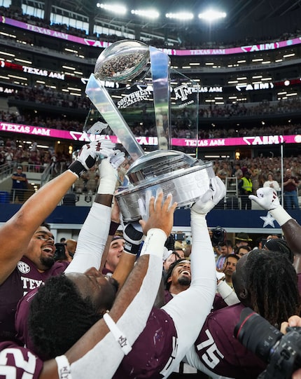 Texas A&M linebacker Taurean York (facing) lifts the Southwest Classic trophy with offensive...