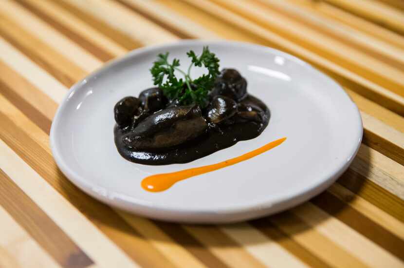 The second course, stuffed squid in black ink sauce, is a traditional Spanish dish. One man...