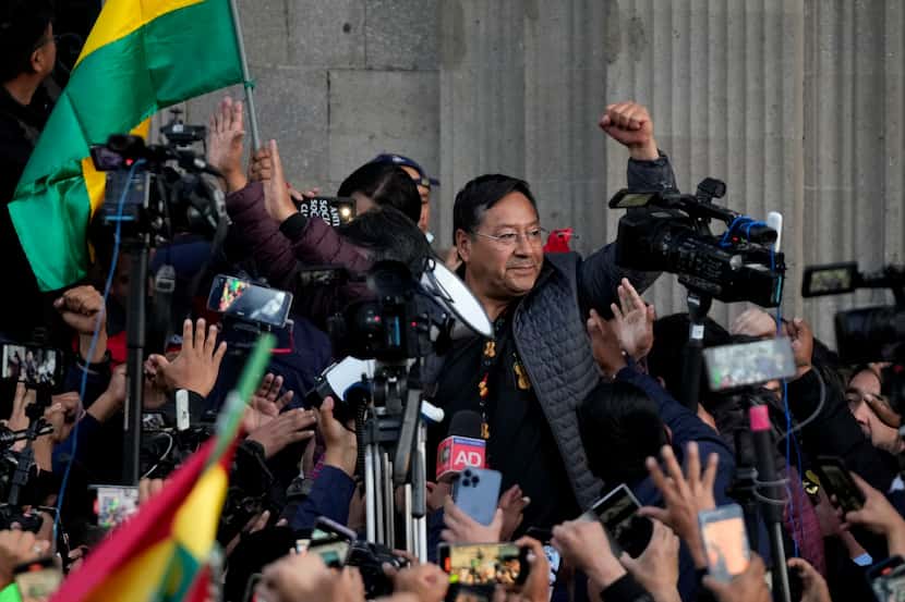 El presidente boliviano Luis Arce levanta un puño cerrado rodeado de partidarios y medios de...