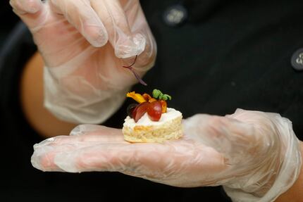 A student adds the finishing touch to the sweet chile fruit baguette appetizer in the...