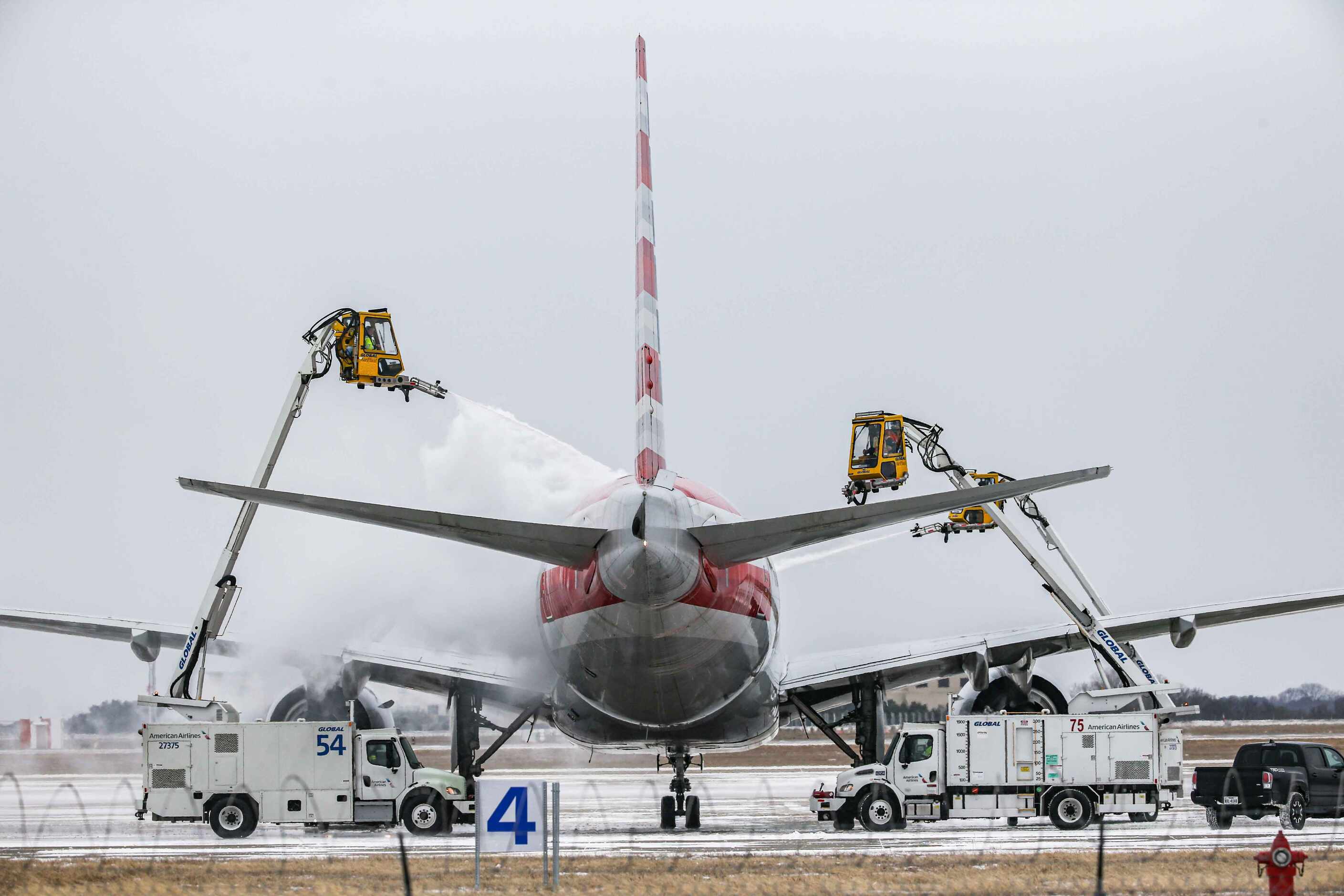 An American Airlines jet is de-iced at DFW International Airport before takeoff as winter...