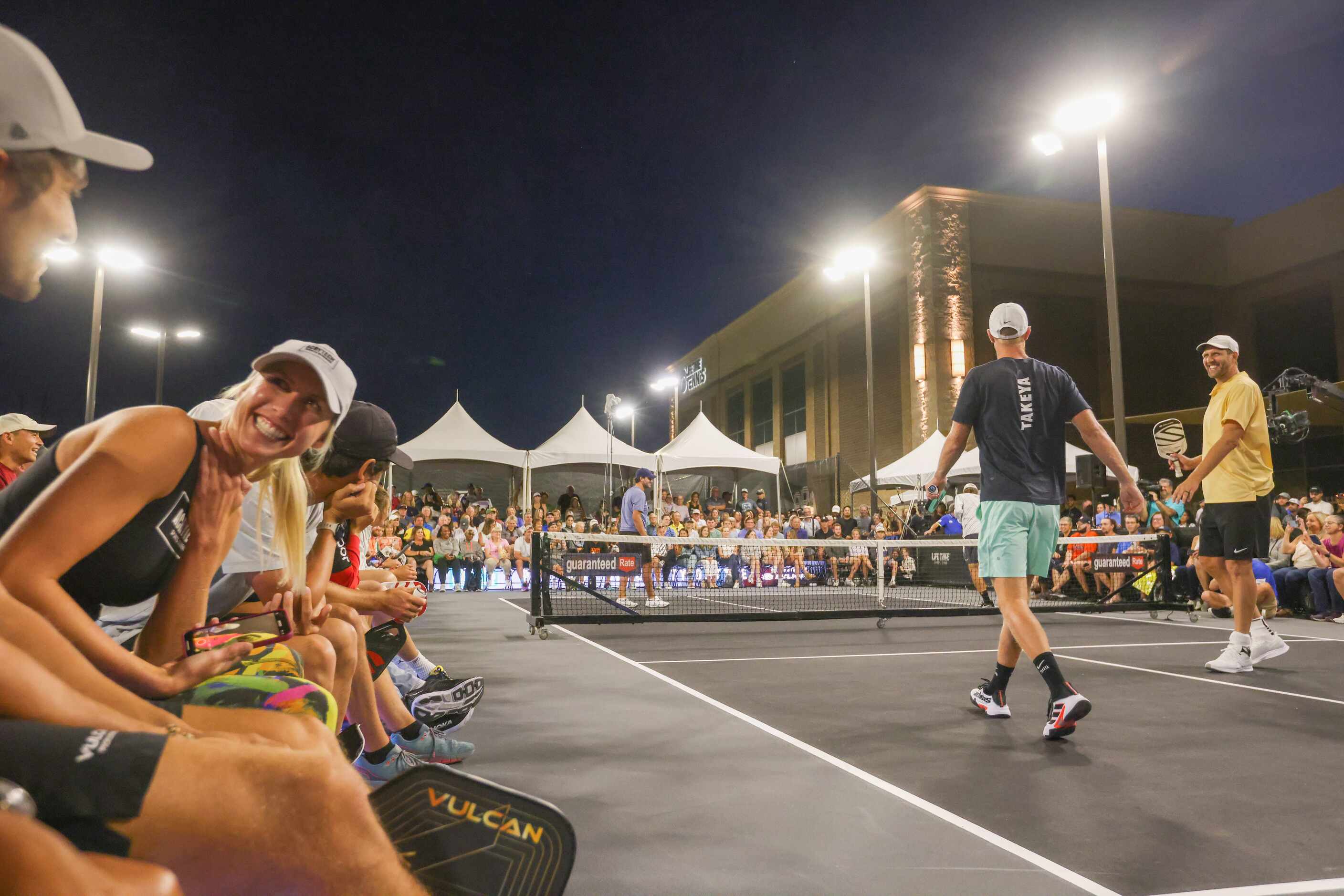 Pickleball players react to a point in the doubles match with Tony Romo (left), Riley Newman...
