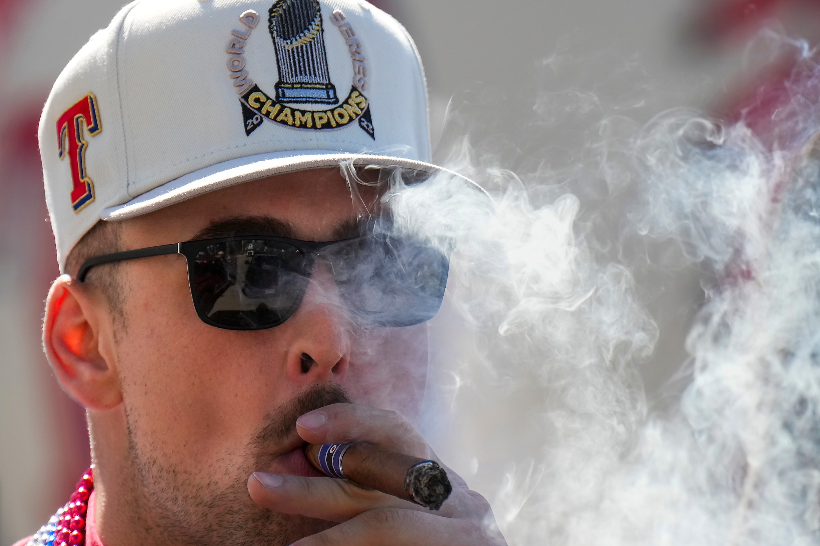 Texas Rangers first baseman Nathaniel Lowe smokes a cigar while riding a truck during the...