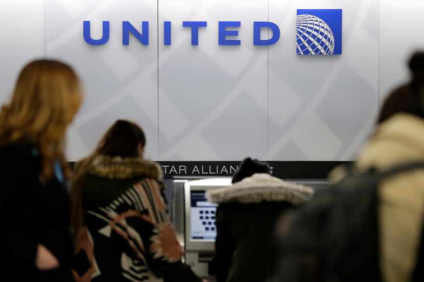 In this Wednesday, March 15, 2017, photo, people stand in line at a United Airlines counter...