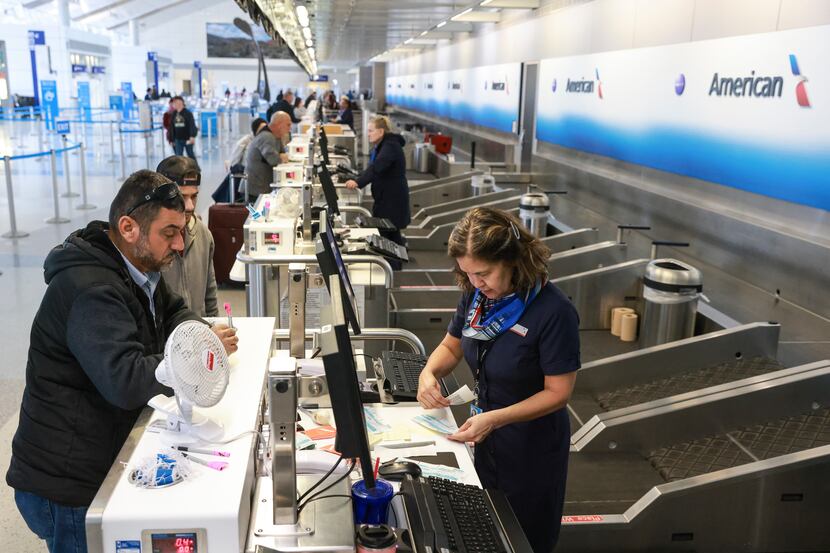 American Airlines customer service worker Maria Sauve (right) helps Hassan Thabaten and his...